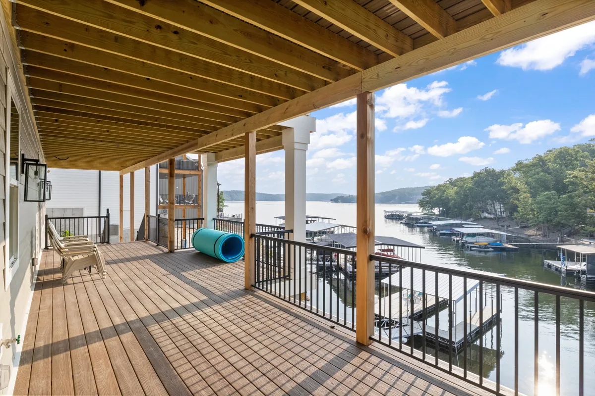 A wooden deck overlooks the lake, with boat docks and a blue inflatable object visible. The setting is ideal for relaxing, boating, and outdoor dining, evoking a leisurely and communal atmosphere.