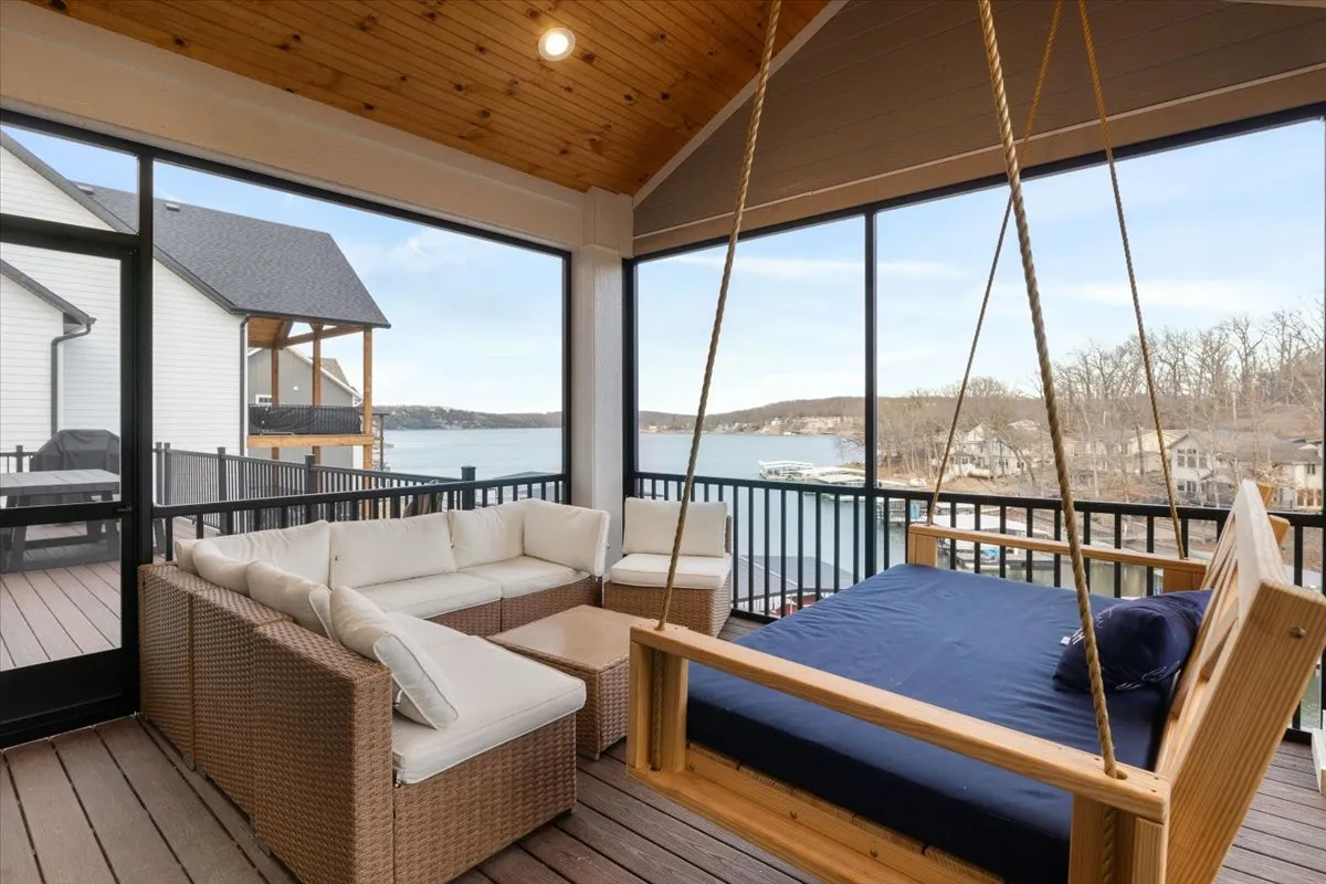 An inviting outdoor seating area with a swing bed overlooking the lake, perfect for relaxing or socializing. The tranquil water view and cozy arrangement evoke a sense of retreat and relaxation right at the lake's edge.