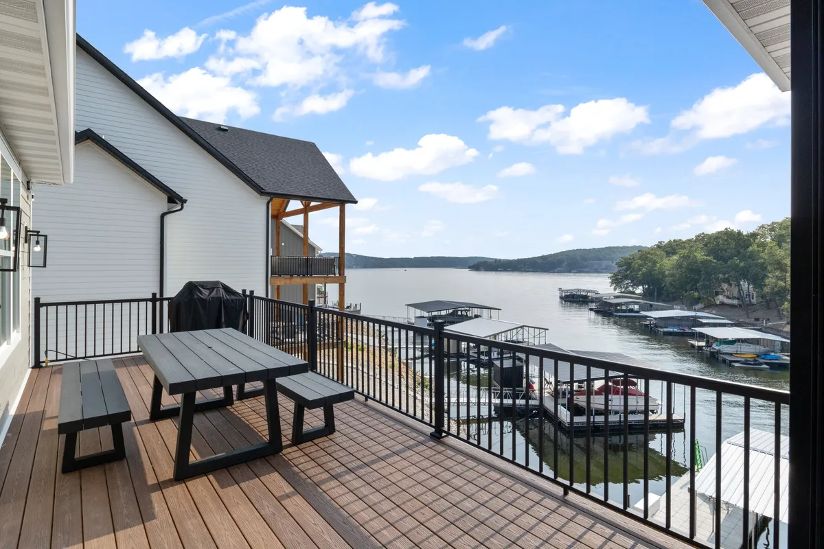 A tranquil wooden upper deck overlooking the lake, with comfortable seating and views of docked boats and distant hills. The expansive sky and water create a serene, inspirational atmosphere perfect for breaks or relaxation after work.