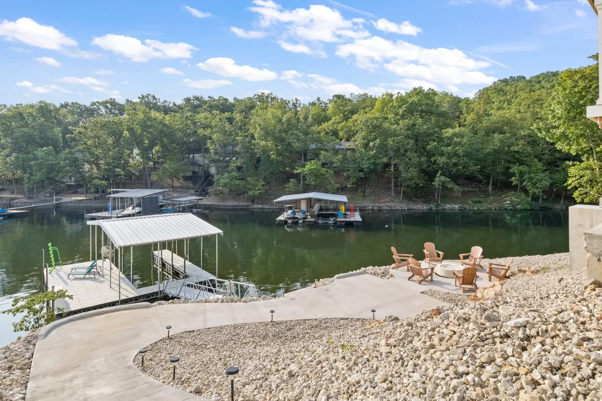 A peaceful lakefront dock with a cozy seating area surrounded by trees, offering direct access to the water. The dock's inviting setup suggests swimming, fishing, and launching water toys, while the tranquil water surface and open space hint at a relaxing outdoor experience.
