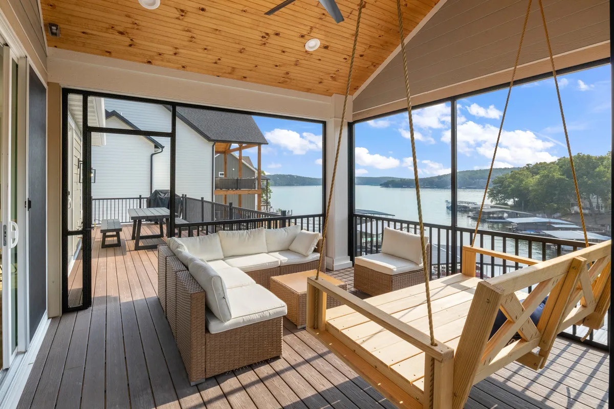 This exterior image features a swing seat and a comfortable seating arrangement on a deck, with a serene view of the lake in the background. The ambiance is tranquil, ideal for socializing, relaxing, or enjoying the scenery.