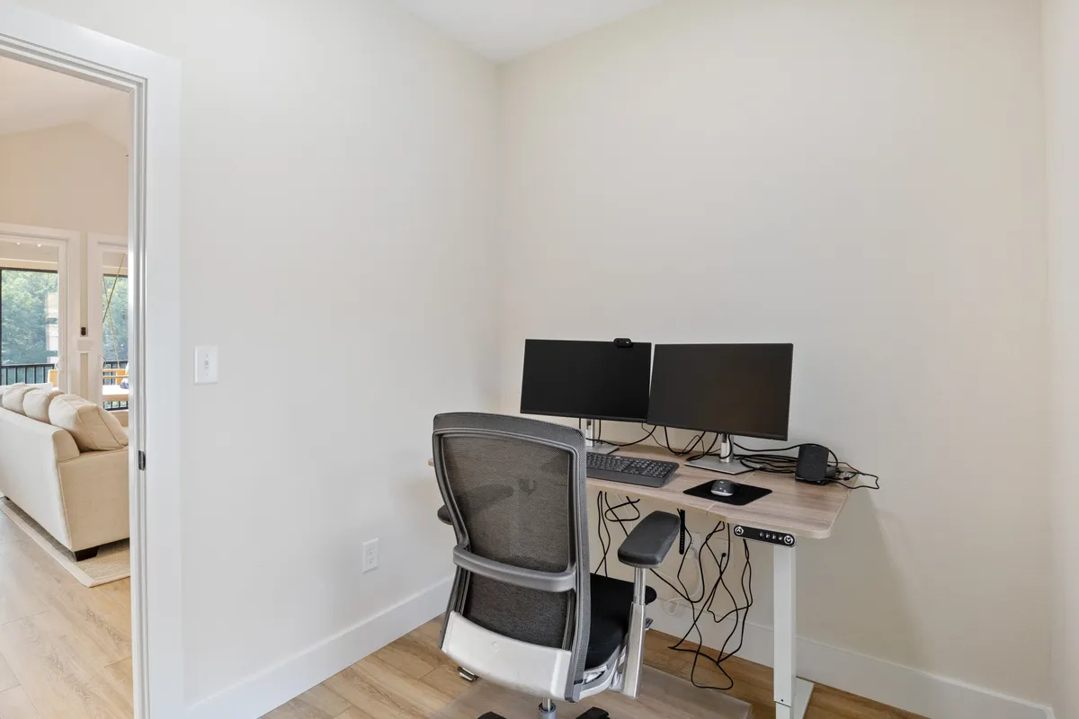 A modern, minimalistic home office setup featuring a desk with dual monitors, an ergonomic chair, and clean, uncluttered decor. The space is bathed in natural light, enhancing the atmosphere for focused and productive work sessions.
